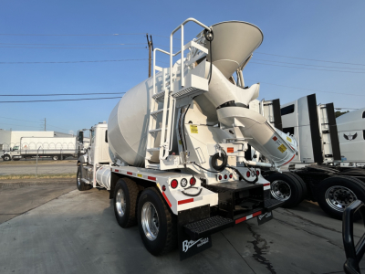 Mack GR64B mixer truck rear view showing cement loading drum and chute, rear tires, and rear access ladder.