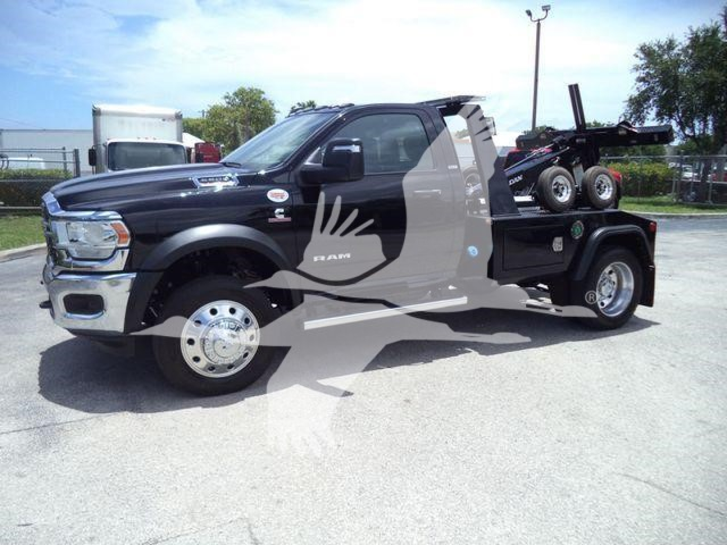Truck side view of a 2024 Ram 5500 SLT with a winch and service bed, black exterior, chrome wheels, logo on door, behind-the-wheel hitch setup.