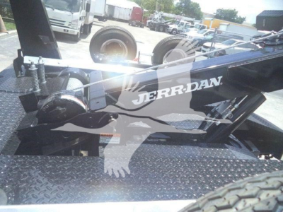 Winch truckattachment showing Jerr-Dan logo on black metal arm with diamond plate platform and dual wheels in background.