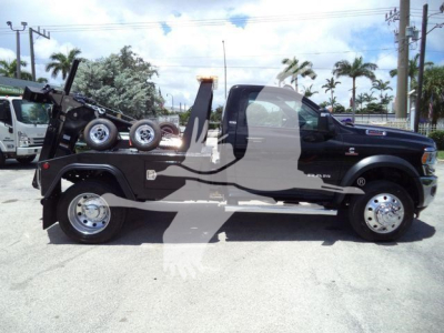 Ram 5500 SLT pickup in side profile with integrated winch and tow setup on flatbed, black exterior, chrome wheels, daytime outdoor lot.