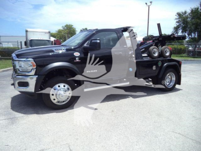 Truck side view of a 2024 Ram 5500 SLT with a winch and service bed, black exterior, chrome wheels, logo on door, behind-the-wheel hitch setup.