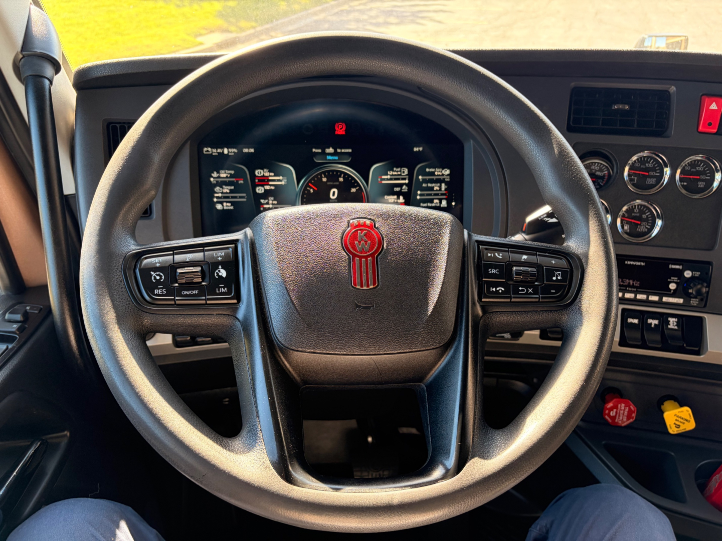 Steering wheel of a Kenworth T680 interior with dashboard gauges and controls visible.
