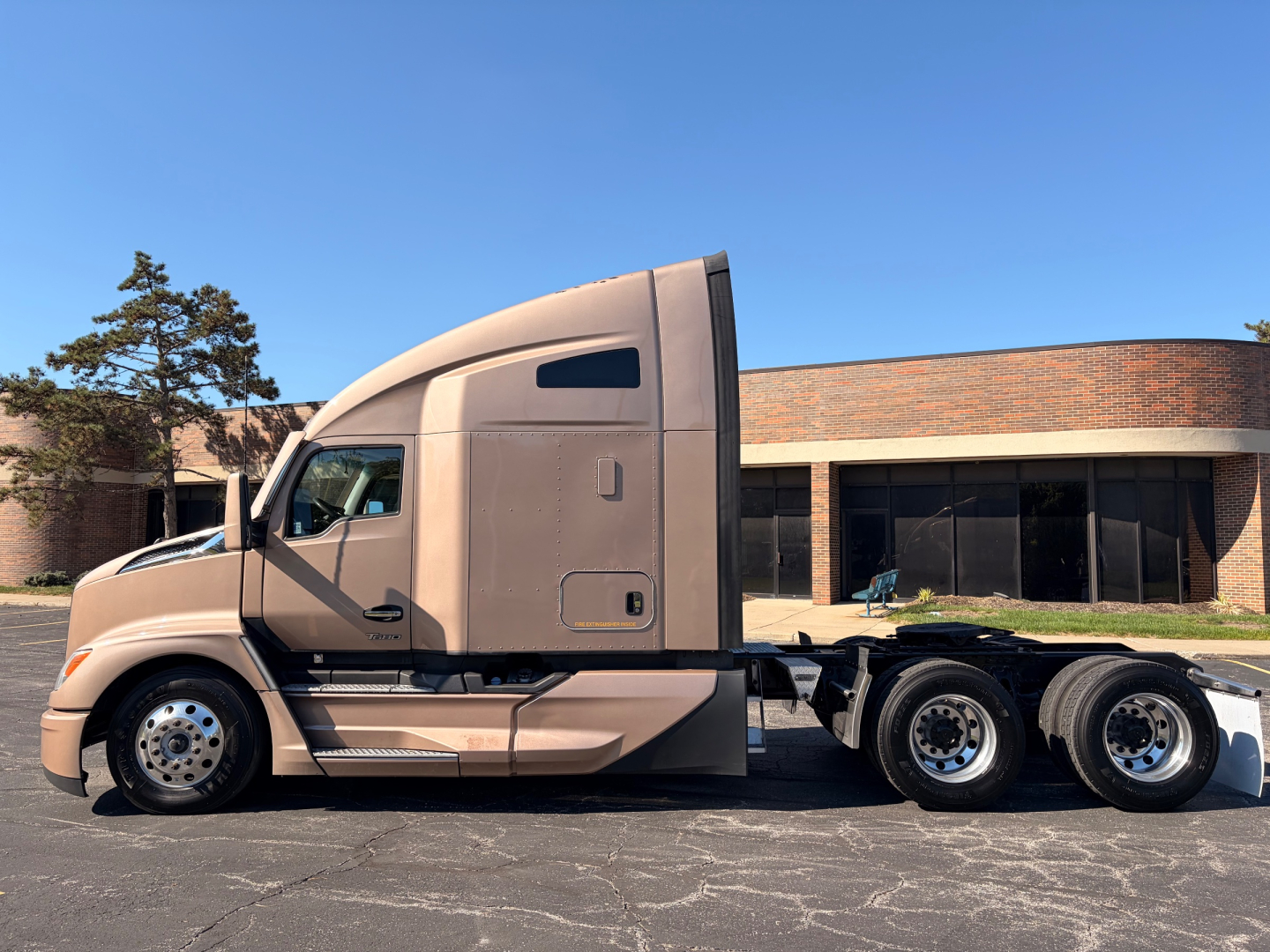 Kenworth T680 tractor with beige cab and sleeper, side view showing tandem rear axles and fuel/tank area.