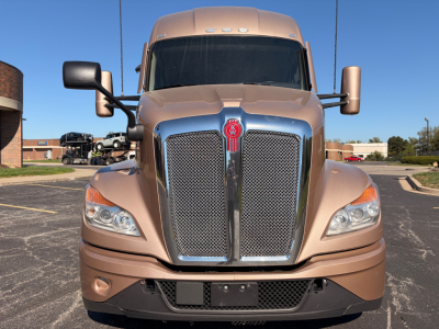 Kenworth T680 front view showing chrome grille badge and headlights, beige/tan exterior, large side mirrors.