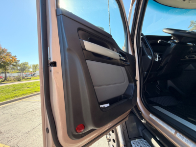 Kenworth T680 truck interior door panel view from open driver door, black and gray interior with beige accents, steering wheel visible.