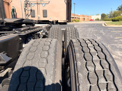Kenworth T680 truck chassis and dual rear axles with visible tires and sleeper cab in background.