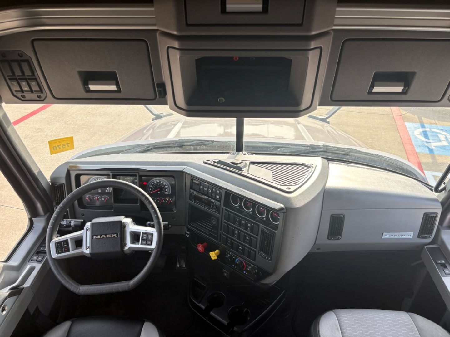 Truck cab interior of a 2023 Mack AN64T70 showing steering wheel, dashboard with gauges, center console, and overhead cab controls.