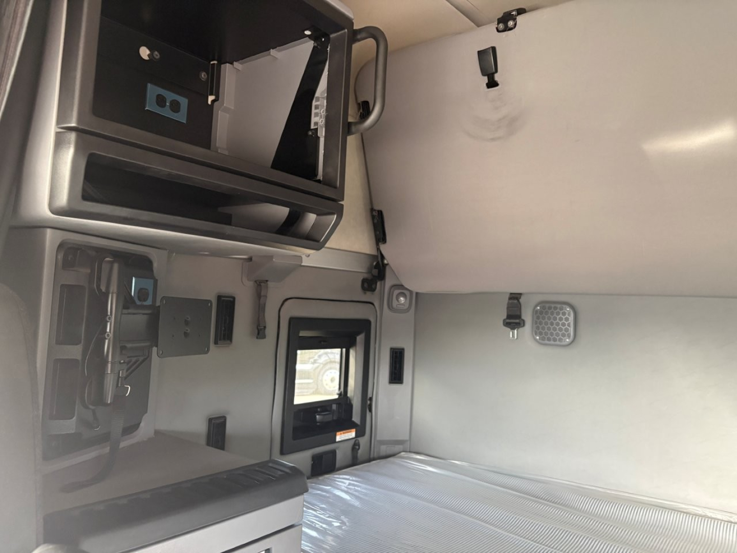 Truck cab sleeper area of a 2023 Mack AN64T70 showing bunk area and overhead compartment with vents and interior panels.