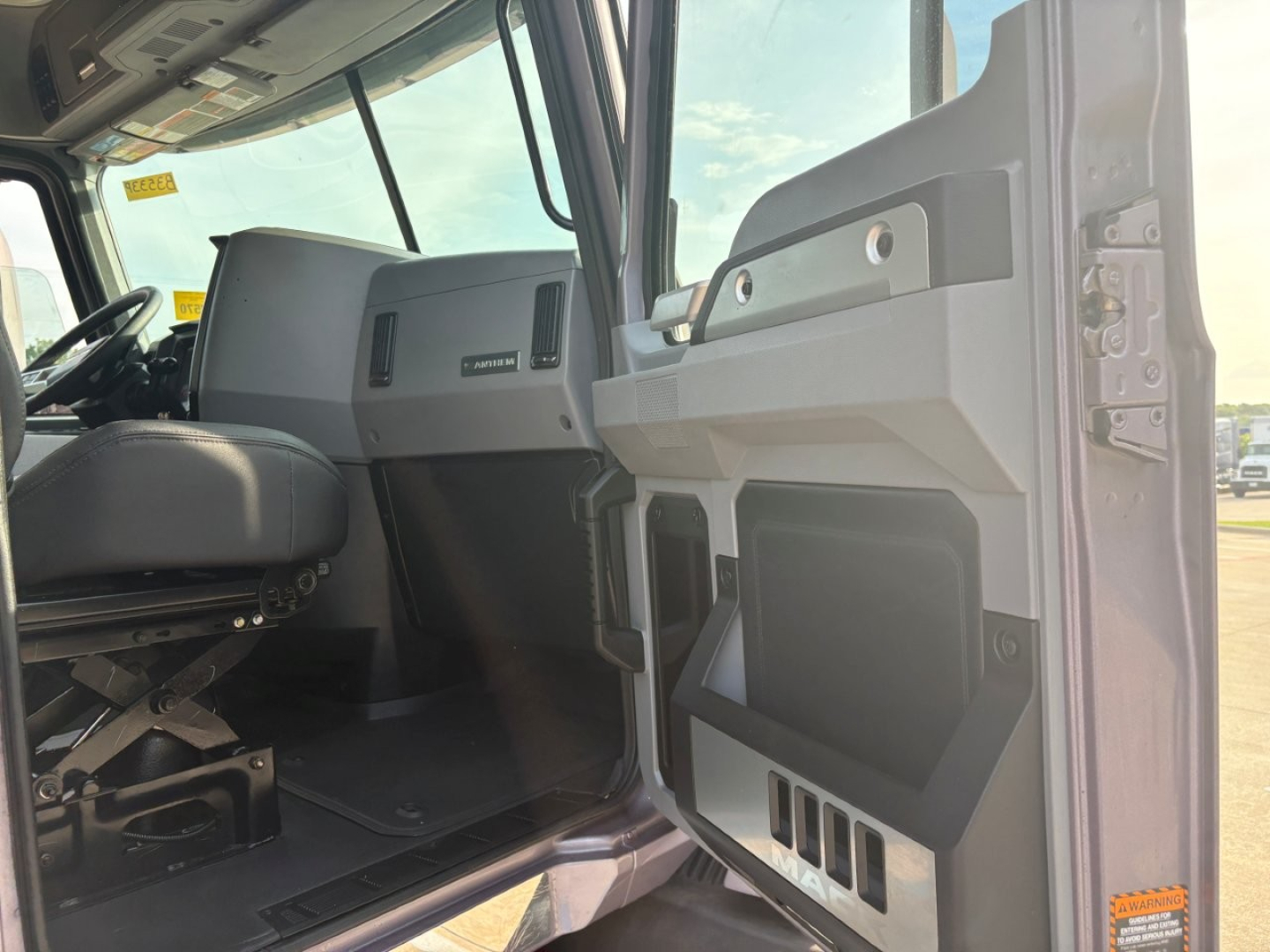Cab interior and driver door of a Mack AN64T70 truck showing dashboard and open door panel.
