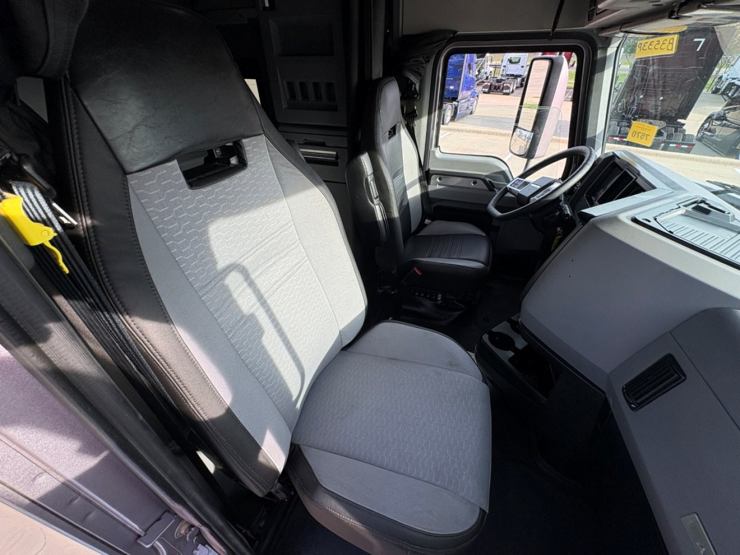 Truck cab interior showing driver seat, passenger seat, and dashboard of a Mack AN64T70. Visible text not legible beyond typical interior features.