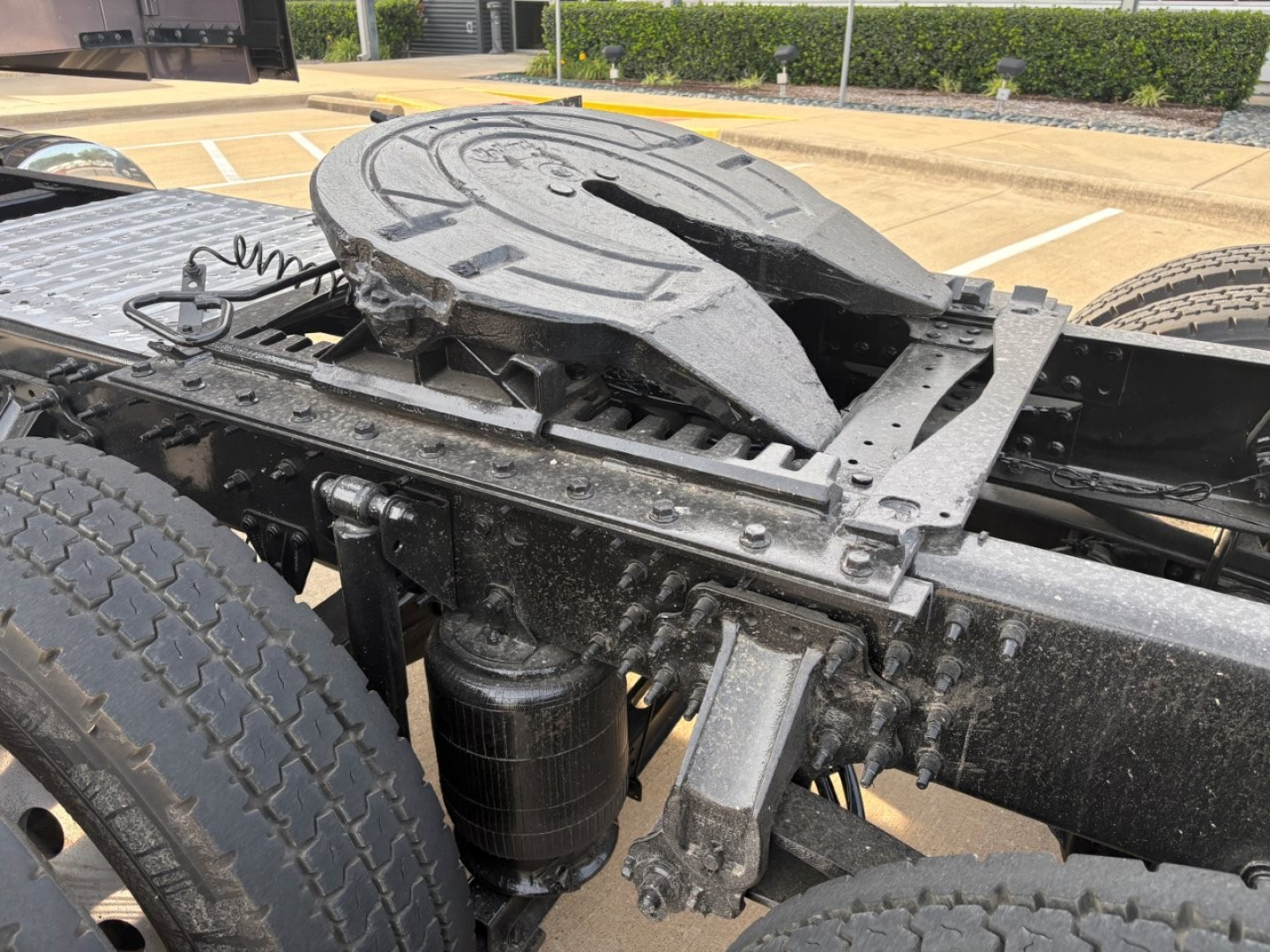 Mack AN64T70 tractor cabless frame showing fifth-wheel kingpin and chassis components; dual rear wheels visible; mechanical linkages and air tank present.
