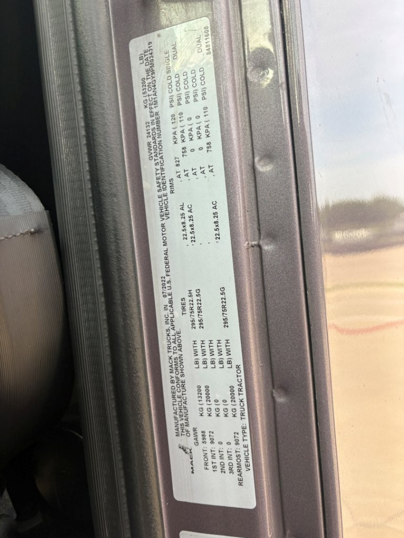 Label with vehicle information plate showing specifications and VIN on Mack AN64T70 truck door jamb including tire and weight data.