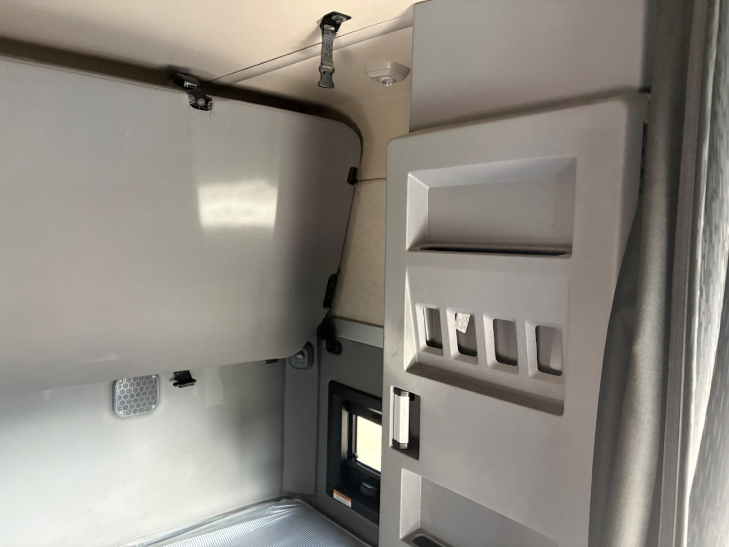 Mack AN64T70 sleeper cab interior showing storage compartments and window area with beige panels.