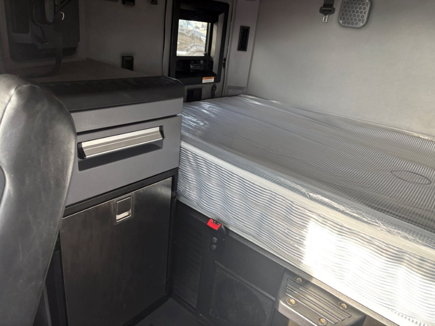 Mack AN64T70 sleeper interior showing aluminum sleeper bed, storage cabinet with drawer, and control panel area.