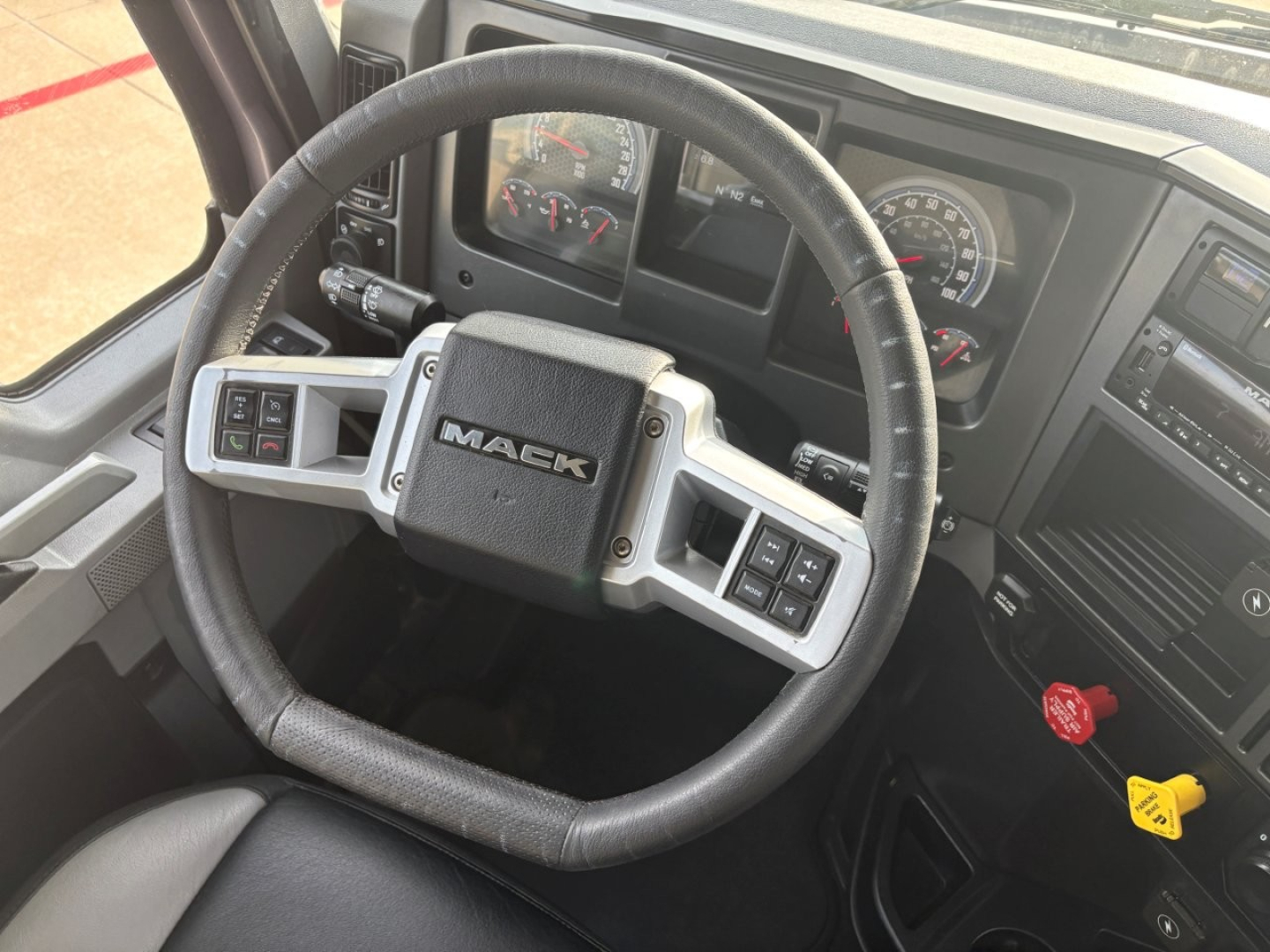Mack AN64T70 truck interior showing steering wheel with Mack logo, instrument cluster, and dashboard controls.