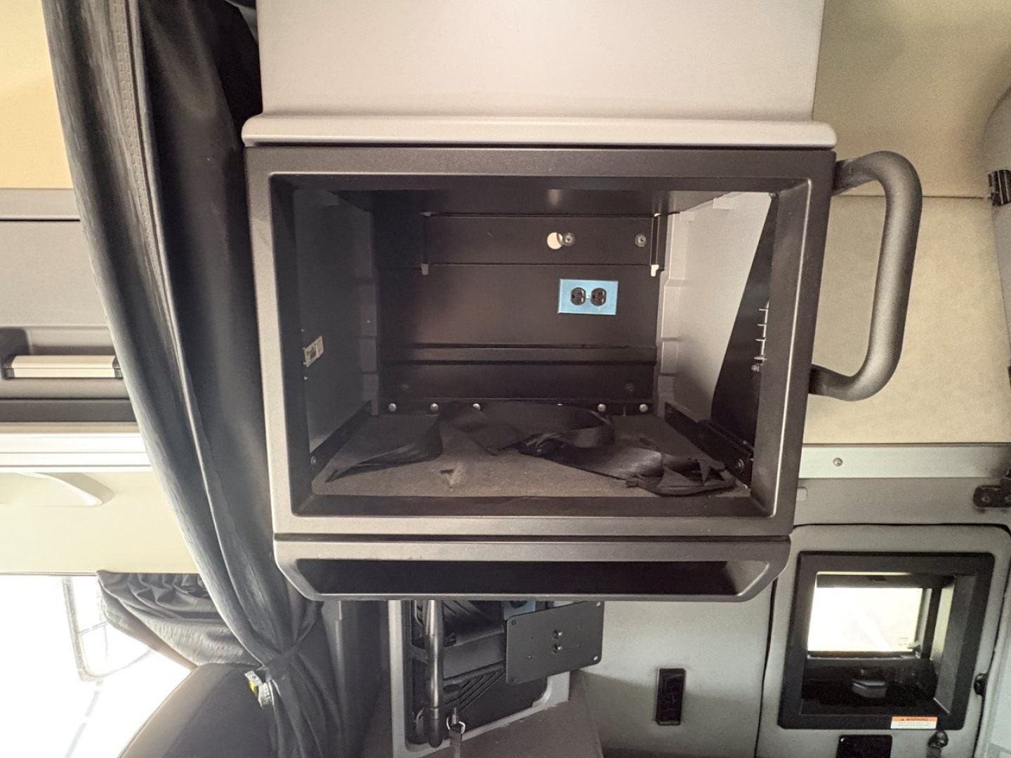 Mack AN64T70 sleeper truck cab interior showing empty storage compartment with blue  electronic panel and handles.