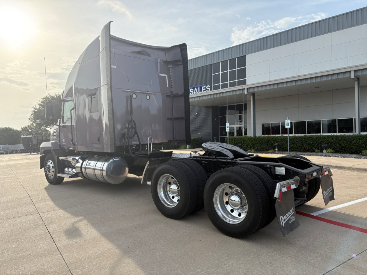 Truck tractor rear view showing dual rear axles, fuel tanks, and sleeper cab with Mack AN64T70 style silhouette.