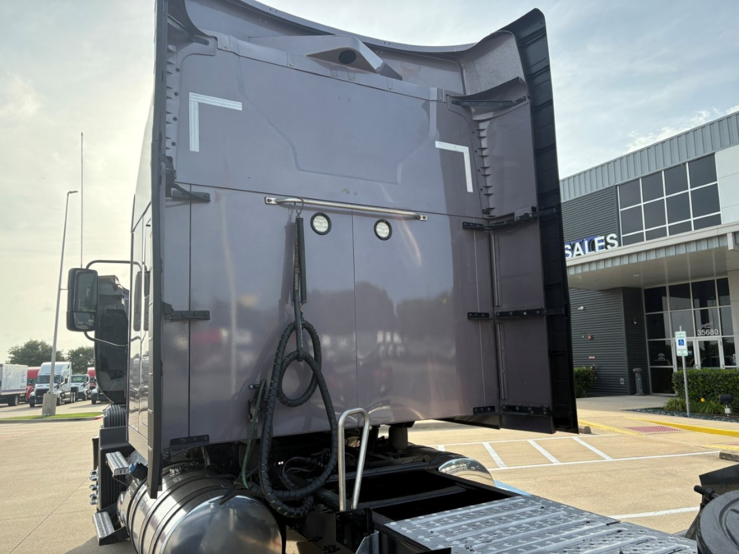 Truck tail with raised bed of a Mack AN64T70 conventional sleeper showing rear doors, hoses, and bumper; no legible text visible.