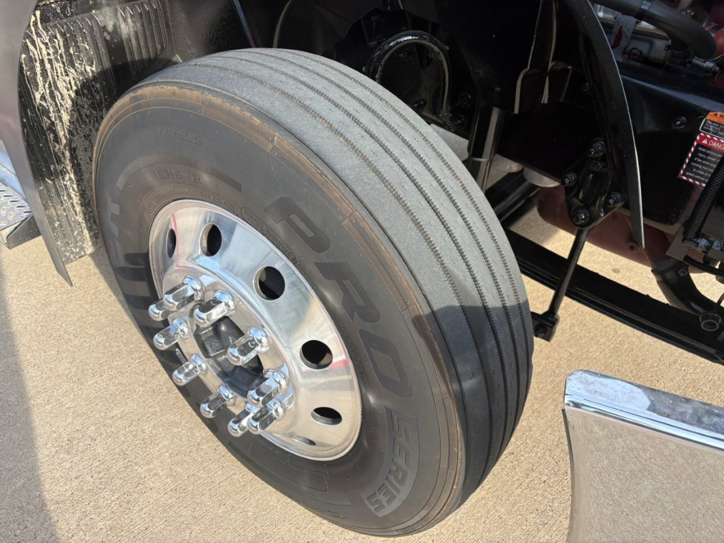 Truck wheel and dual rear axle with large Goodyear tire, polished aluminum hub, lug nuts, and part of the chassis visible.