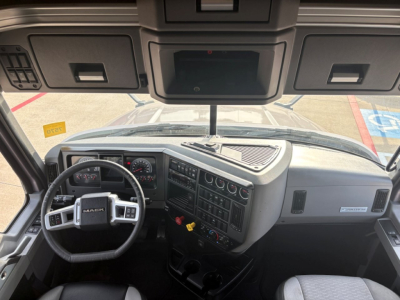 Truck cab interior of a 2023 Mack AN64T70 showing steering wheel, dashboard with gauges, center console, and overhead cab controls.
