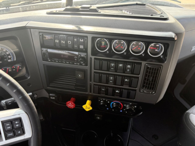 Dashboard of a Mack AN64T70 truck showing gauges, switch panels, and ignition area with steering wheel visible.