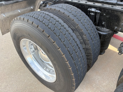 Mack AN64T70 truck dual rear tires with chrome wheel rims and suspension components visible; portion of chassis and frame undercarriage.