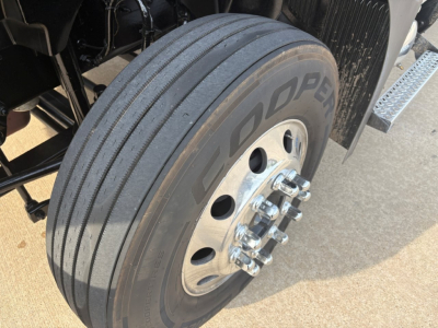 Dual rear axle wheel and tire of a Mack AN64T70 sleeper cab showing Goodyear tire with chrome lug nuts and aluminum wheel.