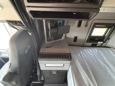 Interior of a Mack AN64T70 truck sleeper showing a control panel with a small screen, storage drawer, and a bed with striped cover visible.