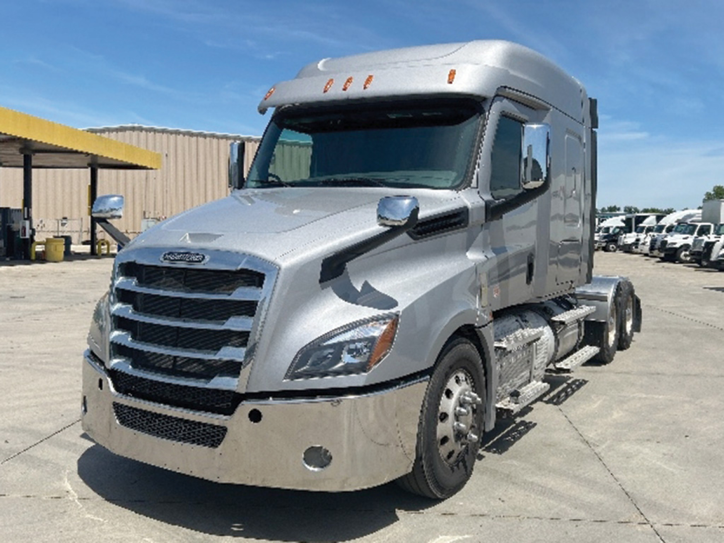 Freightliner Cascadia126 semi-truck cab in silver parked in lot, front three-quarter view with chrome grille and sleeper cab