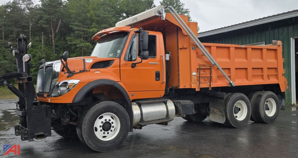 Orange 2009 International WorkStar 7600 dump truck with plow and sander, side view in wet conditions.