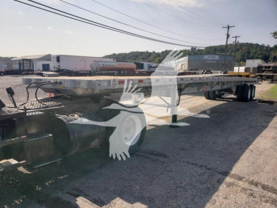 Flatbed trailer showing long aluminum bed with dual rear axles and wheel wells, stock number VED49012 visible, VIN 7KYFB4828VED49012 in listing.