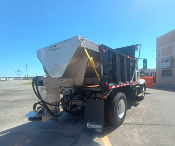 Truck rear three-quarter view showing dump bed on a Mack MD7 chassis with plow equipment and hydraulic lines visible.