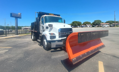 Mack MD7 truck with orange snow plow blade attached, side view in dealership lot.