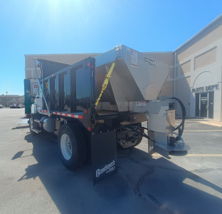 Truck bed with plow equipment attachment showing side view of a Mack MD7 dump body hopper and hydraulic components.