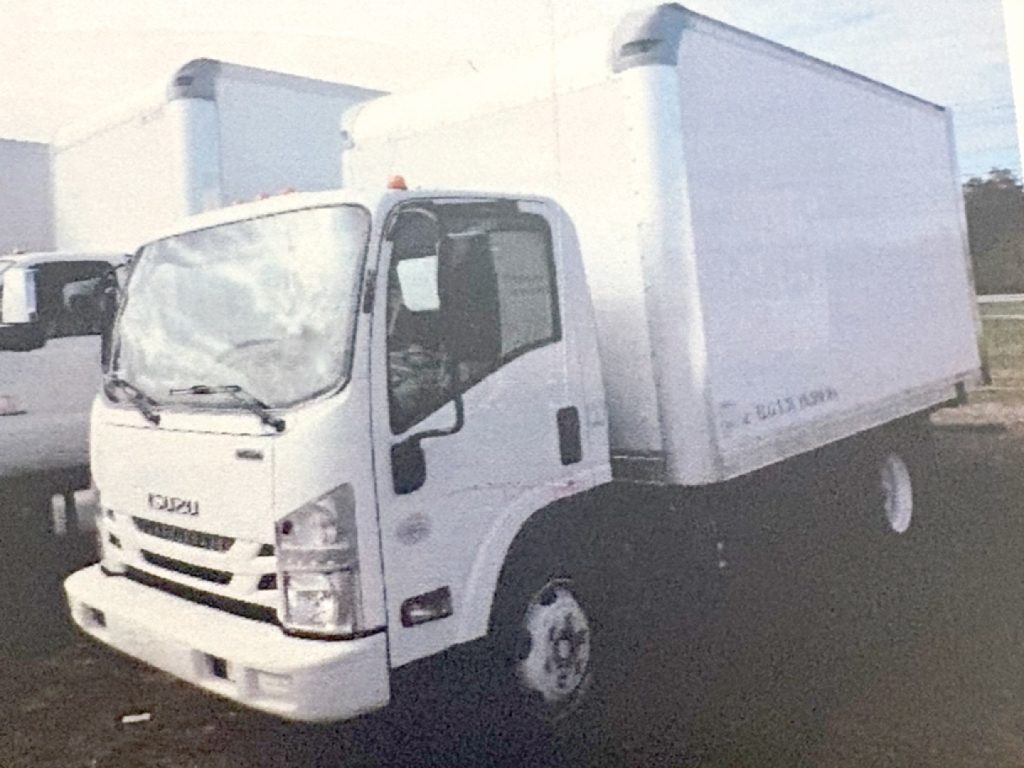 Isuzu NPR cabover truck in a used inventory lot with a box body, front view showing cab and cargo box.