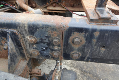  Freightliner cab and chassis frame showing rusted bolts and metal crossmember with welded brackets.