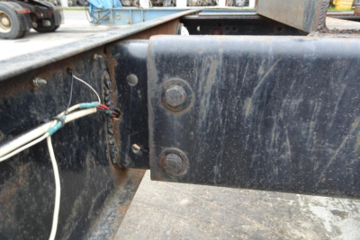 Freightliner cab and chassis rear frame area showing mounting plates, dirt, and exposed wiring harness near the frame rail.