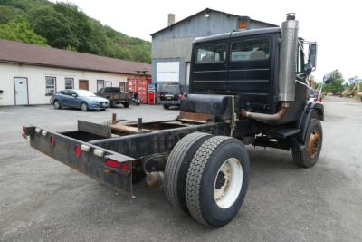 Freightliner FL70 cab and chassis rear view showing dual rear tires, flatbed hitch, and exhaust stack