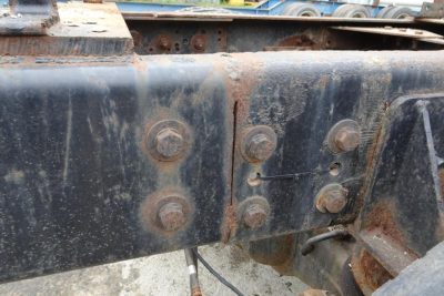 Truck chassis frame showing rusty bolt connections and mounting brackets on a Freightliner/Chassis undercarriage.