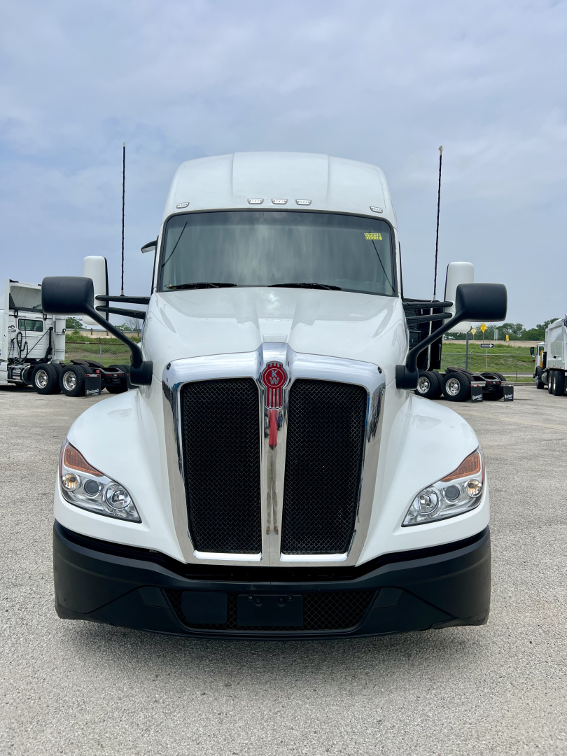 Kenworth T680 front view showing bold chrome grille, white cab, black bumper, large side mirrors.