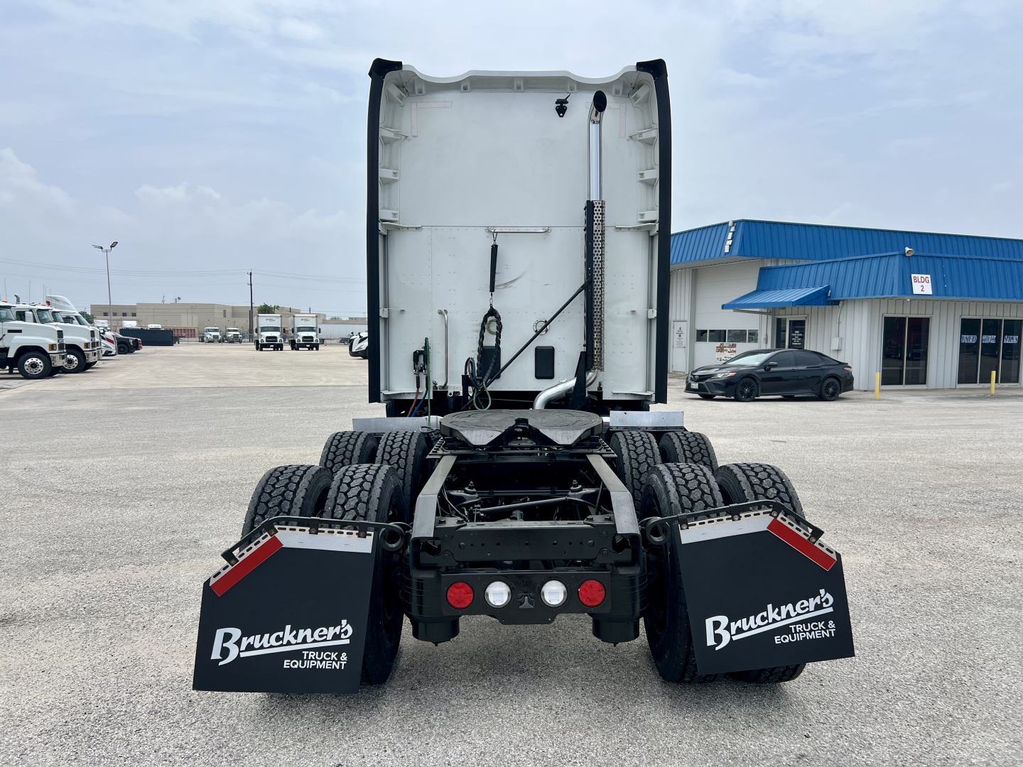 Kenworth T680 rear view with fifth wheel and dual rear axles, Bruckner’s mudflaps, chassis and cab-back soil. Visible components include rear bumper, taillights, air lines, and mud flaps.