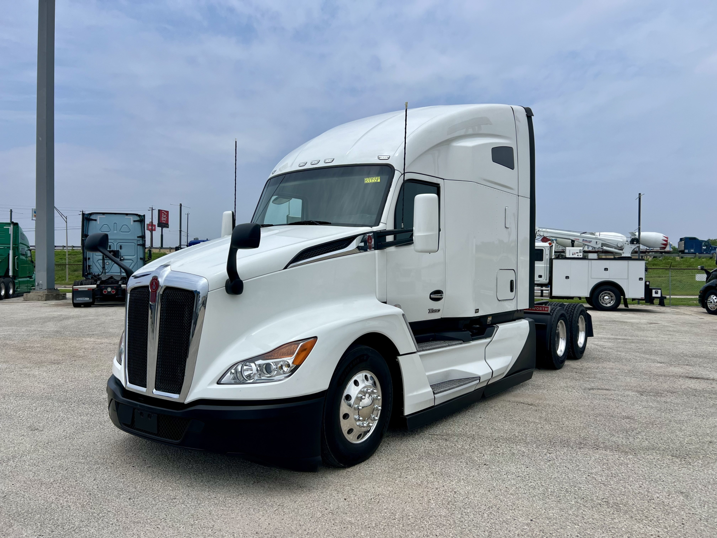 Kenworth T680 tractor-trailer in white, three-quarter view from front-left showing aerodynamic cab, large grille, headlights, side mirrors, and tandem rear axles.