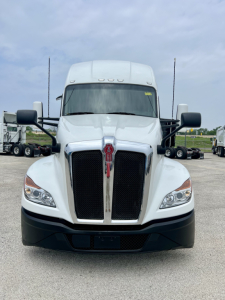 Kenworth T680 front view showing bold chrome grille, white cab, black bumper, large side mirrors.