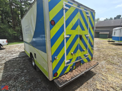 Ford E-350 cargo van rear view with blue-yellow chevron pattern and rear doors open, cargo ramp/step visible.