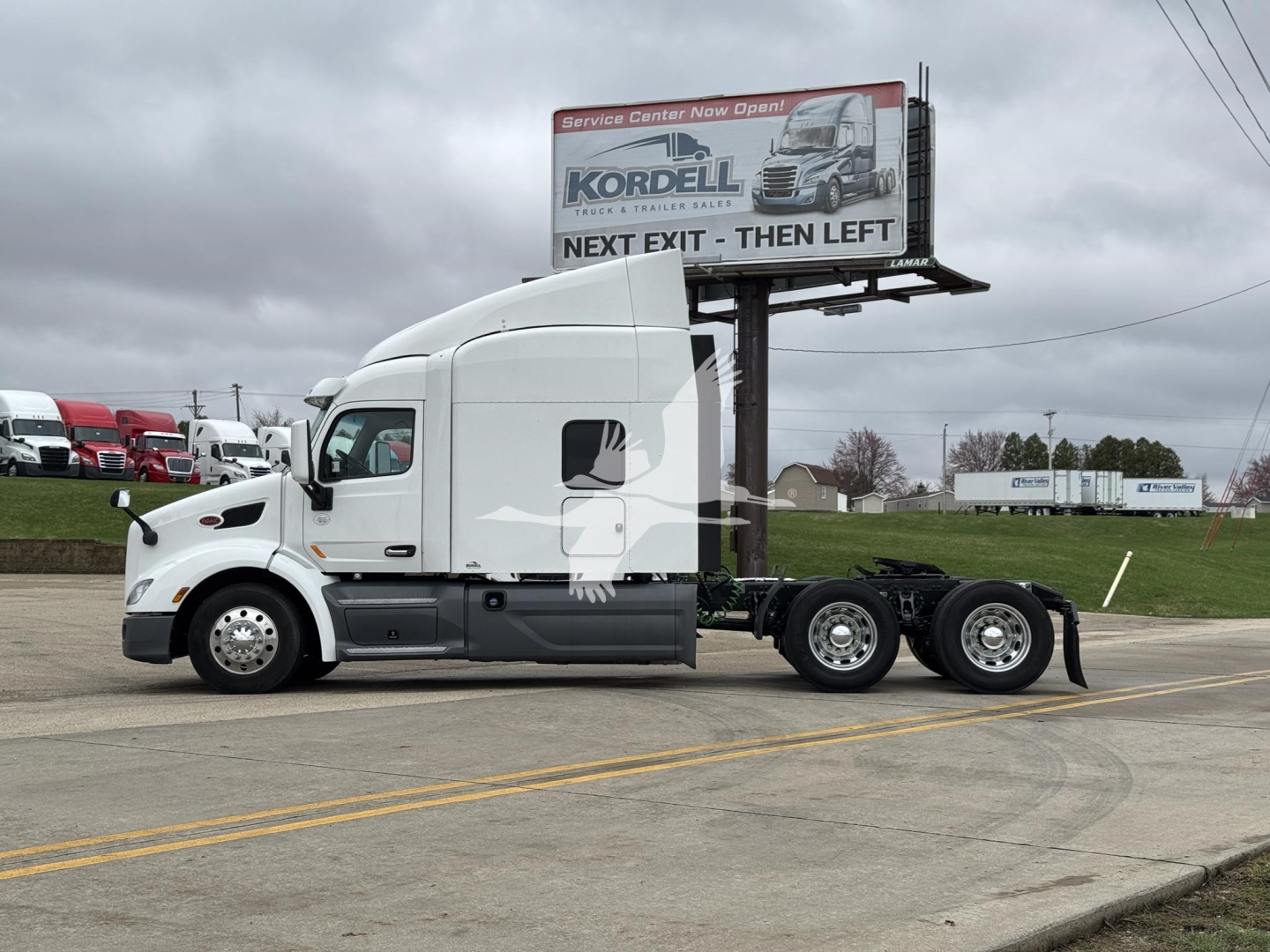 2019 Peterbilt 579 truck tractor side view showing sleeper cab and rear axles with white exterior.