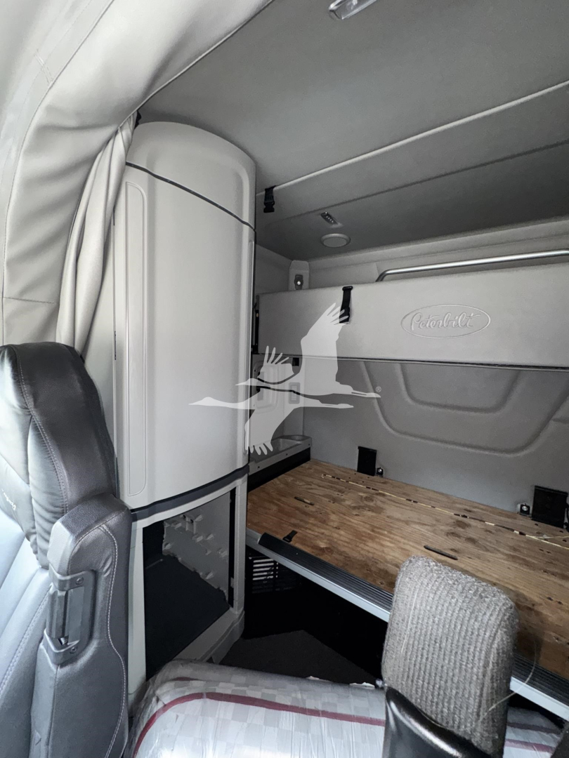 Truck cab interior showing sleeper area with wood floor panel and storage cabinet.