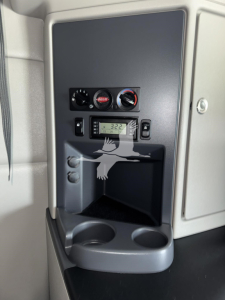 Peterbilt 579 cab interior showing controls dashboard with gauges and a small display, cup holder and storage area.