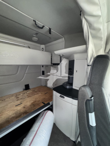 Peterbilt 579 cab interior showing sleeper bunk area and storage cabinet with overhead shelf and small desk area
