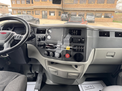 Peterbilt 579 dashboard and steering wheel view showing instrument cluster, center console with switches, and gray interior trim.