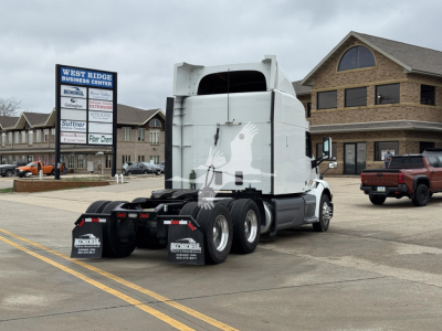Peterbilt 579 tractor in a dealer lot, rear view showing sleeper cab and fifth wheel, with dealership sign in background